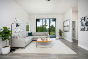 Living room with light gray sectional sofa, wooden coffee table, area rug, plants, and sliding glass door.