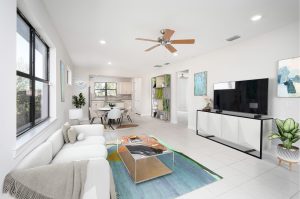 Open living space with white sofa, glass coffee table, TV console, dining area, and kitchen.