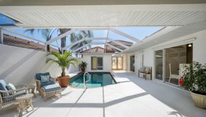 Screened-in patio with small rectangular pool, wicker seating, potted plants, and sliding glass doors.